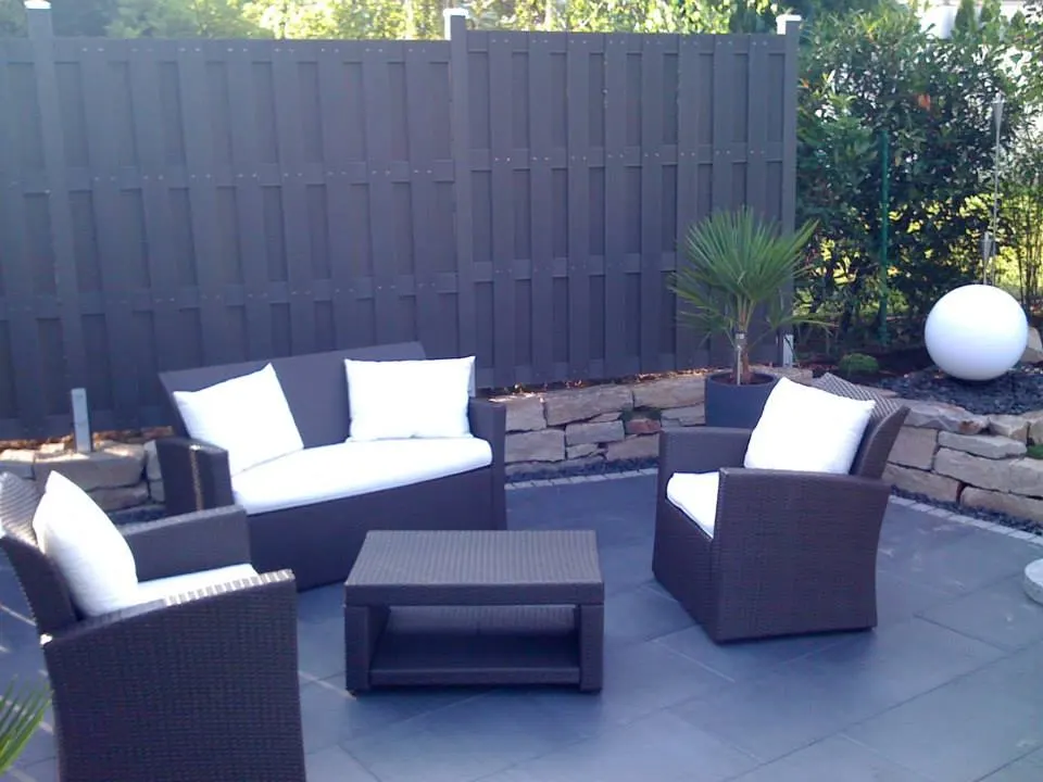 Großzügige Terrasse mit grauem Zaun und Solitärpflanze